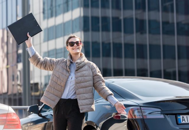 devojka pored automobila sa podignutom fasciklom u ruci