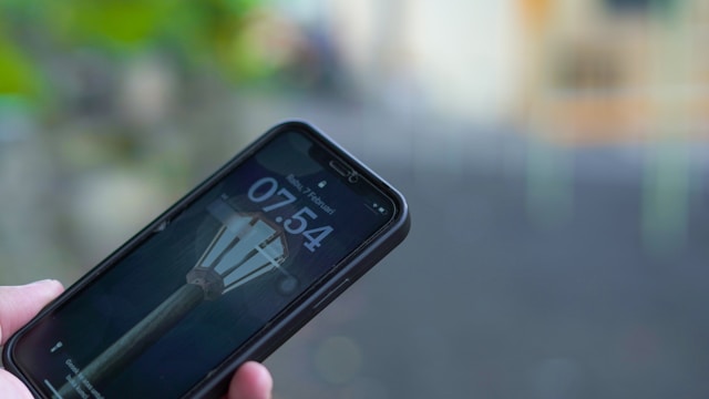 Telefon u ruci prikazuje zaključani ekran sa vremenom 07:54
